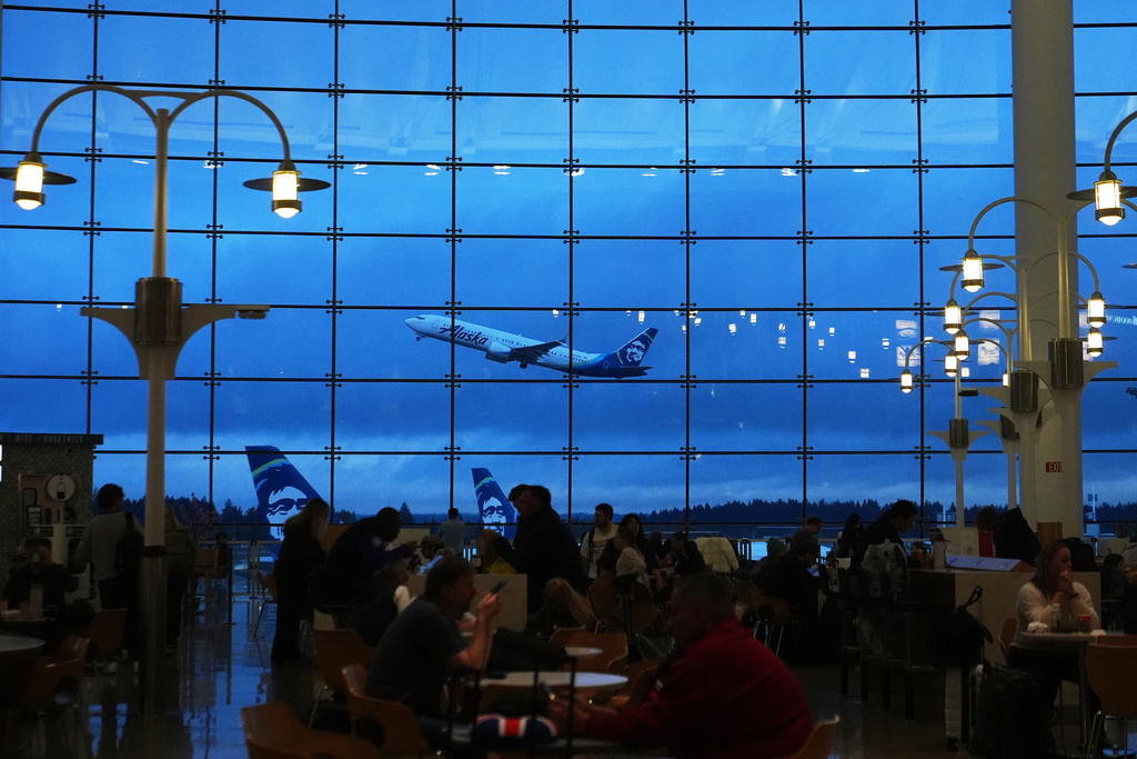 An Alaska Airlines airplane is seen from the central terminal as it takes off at Seattle-Tacoma International Airport Sunday, Nov. 23, 2025, in SeaTac, Wash. (AP Photo/Lindsey Wasson)