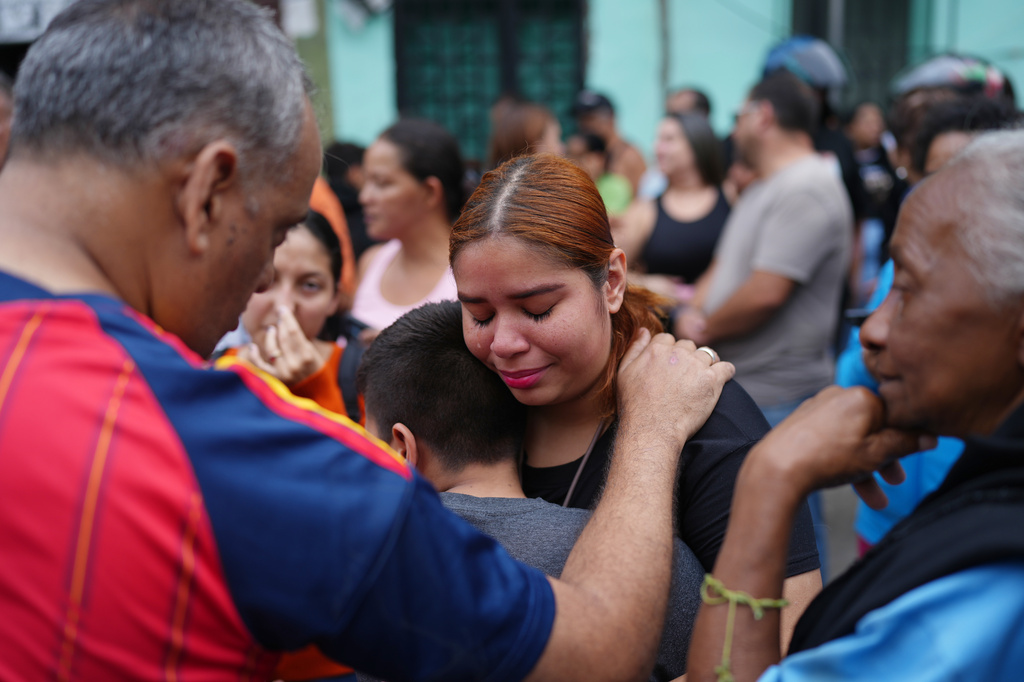 Neighbors stand outside the San Judas Tadeo school after part of the building collapsed in Caracas, Venezuela, Friday, July 3, 2026, days after it was damaged by the earthquakes. (AP Photo/Ariana Cubillos)