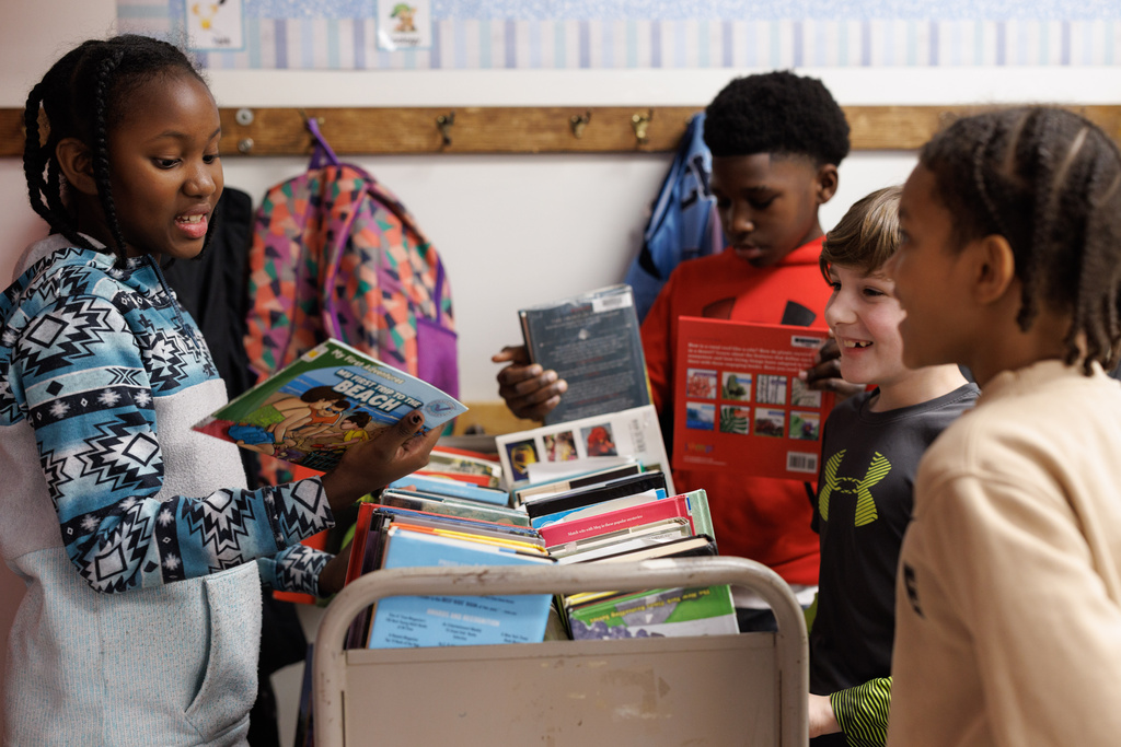 Fifth-grader Orchidee Augustave, left, works with her classmates to clean and stack books for their MicroSociety venture, Paws and Pages, at Clairton Education Center in Clairton, Pa., on Thursday, Jan. 22, 2026. (Quinn Glabicki/Pittsburgh's Public Source via AP)