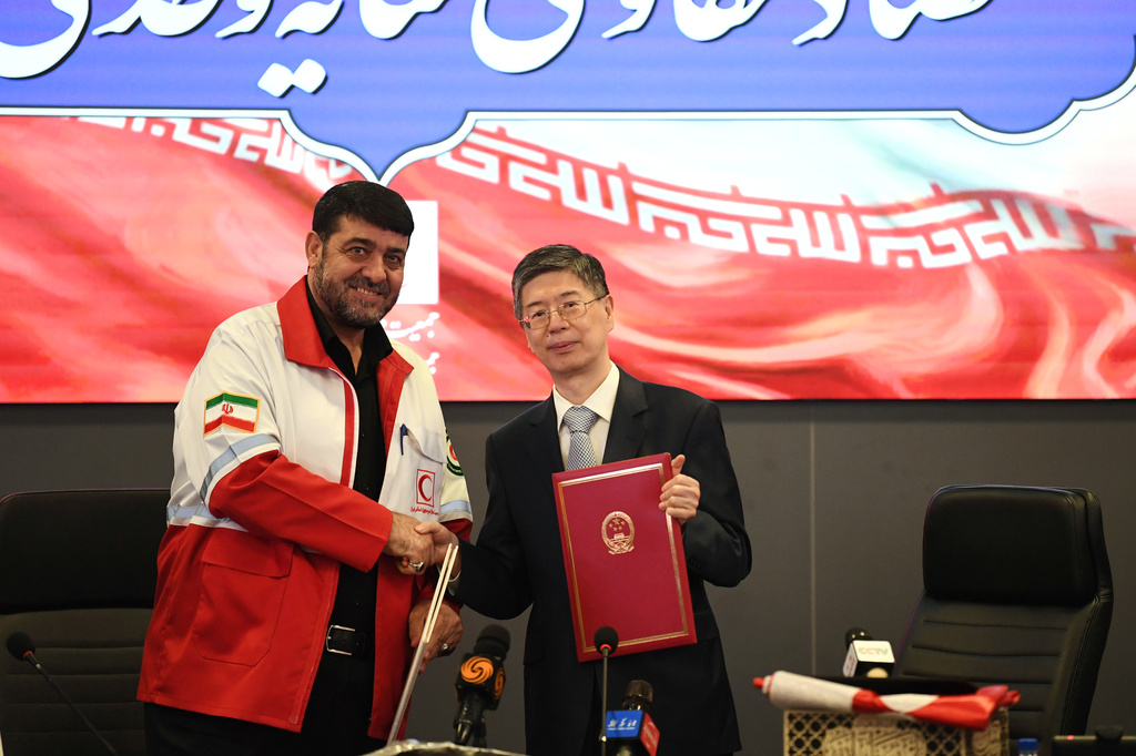 In this photo released by Xinhua News Agency, Chinese Ambassador to Iran Cong Peiwu, right and Iranian Red Crescent Society (IRCS) President Pirhossein Kolivand attend a signing ceremony for the handover certificates of China's emergency humanitarian assistance to Iran in Tehran, Iran, April 15, 2026. (Shadati/Xinhua via AP)