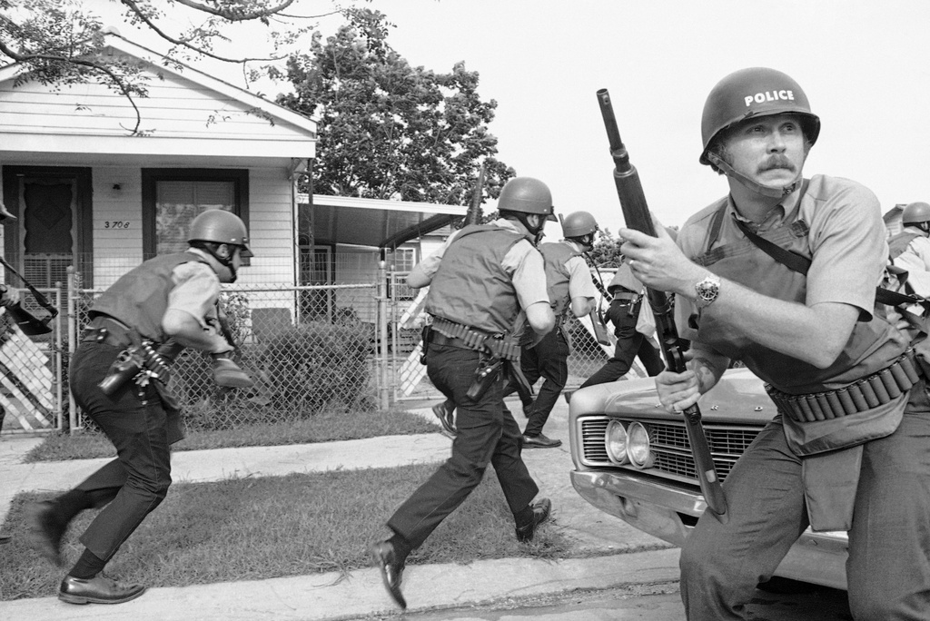 FILE - New Orleans police officers try to keep their heads down as they move in on a Black Panther headquarters during an exchange of gunfire in New Orleans, Sept. 15, 1970. (AP Photo/Jack Thornell, File)