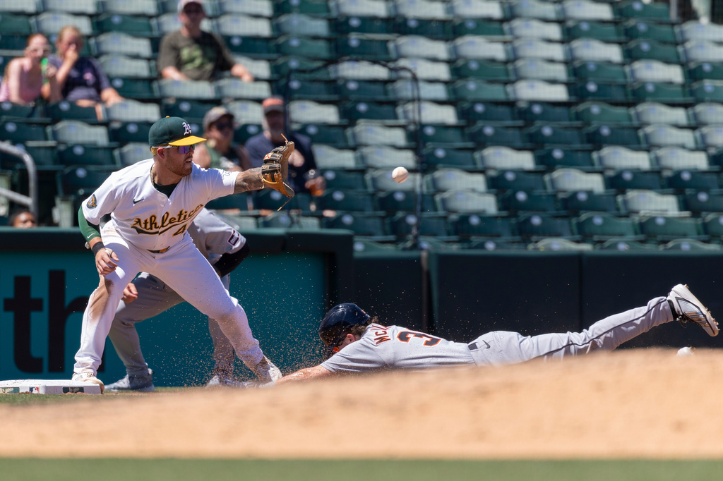 Athletics third baseman Tommy White, left, attempts to put out Detroit Tigers' Zach McKinstry during the fourth inning of a baseball game Sunday, Aug. 2, 2026, in West Sacramento, Calif. (AP Photo/Sara Nevis)