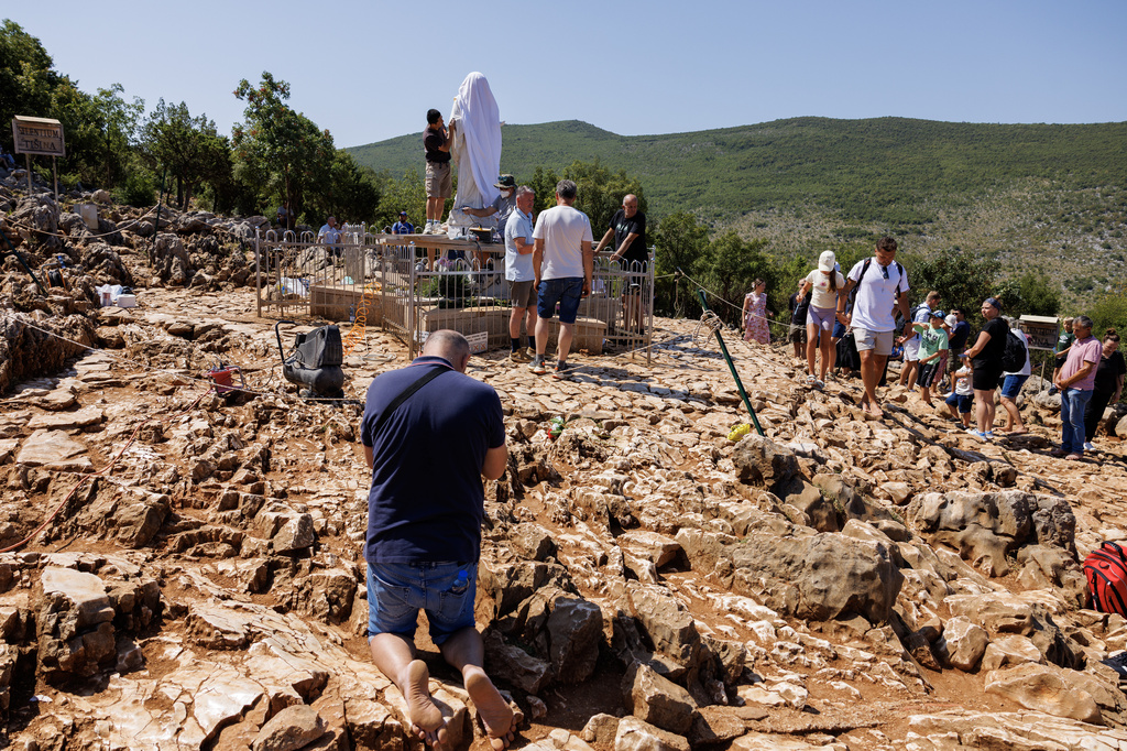 Pilgrims pray next to the vandalized statue of the Virgin Mary, which has been covered with a white sheet, on Apparition Hill in Medjugorje, Bosnia, Tuesday, July 28, 2026. (AP Photo)