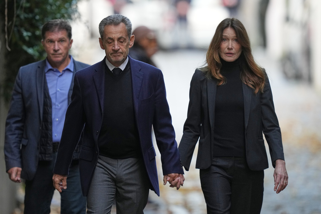Former French President Nicolas Sarkozy and his wife Carla Bruni-Sarkozy leave their home Tuesday, Oct. 21, 2025 in Paris as Nicolas Sarkozy heads to prison to serve time for a criminal conspiracy to finance his 2007 election campaign with funds from Libya. (AP Photo/Thibault Camus)