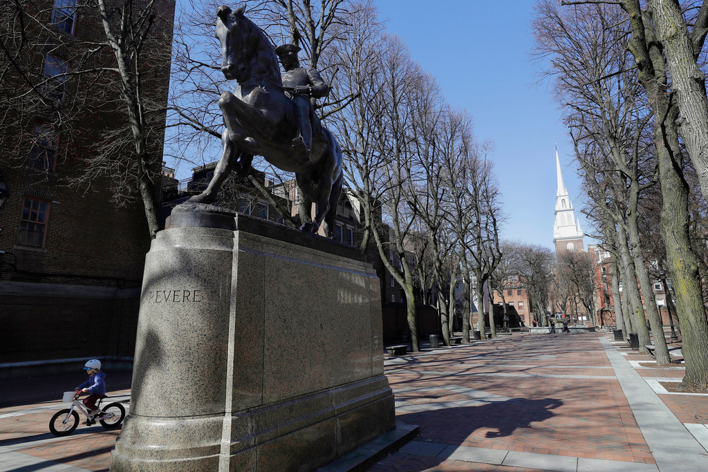 FILE - A child rides a bicycle, left, near a statue of Paul Revere in Boston's North End neighborhood on March 15, 2020. (AP Photo/Steven Senne, File)