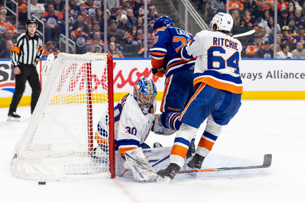 New York Islanders' Calum Ritchie (64) checks Edmonton Oilers' Curtis Lazar (20) in front of Islanders' goalie Ilya Sorokin (30) during the second period of an NHL hockey game in Edmonton, Alberta, Thursday, Jan. 15, 2026. (Timothy Matwey/The Canadian Press via AP)