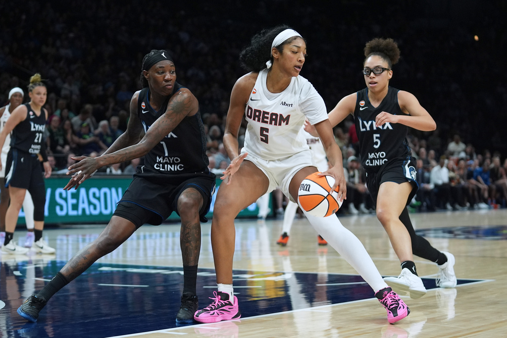 Atlanta Dream forward Angel Reese (5) handles the ball as Minnesota Lynx forward Natasha Howard (1) and guard Olivia Miles (5) defend during the second half of a WNBA basketball game Wednesday, May 27, 2026, in Minneapolis. (AP Photo/Abbie Parr)