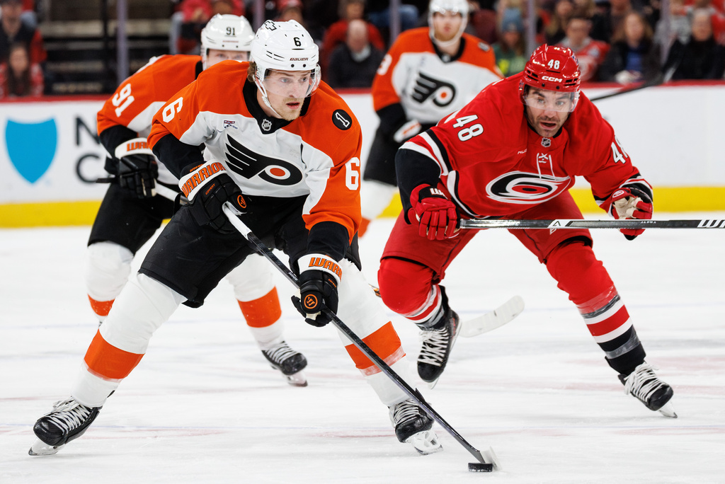 Philadelphia Flyers' Travis Sanheim (6) handles the puck ahead of Carolina Hurricanes' Jordan Martinook (48) during the first period of an NHL hockey game in Raleigh, N.C., Sunday, Dec. 14, 2025. (AP Photo/Ben McKeown)