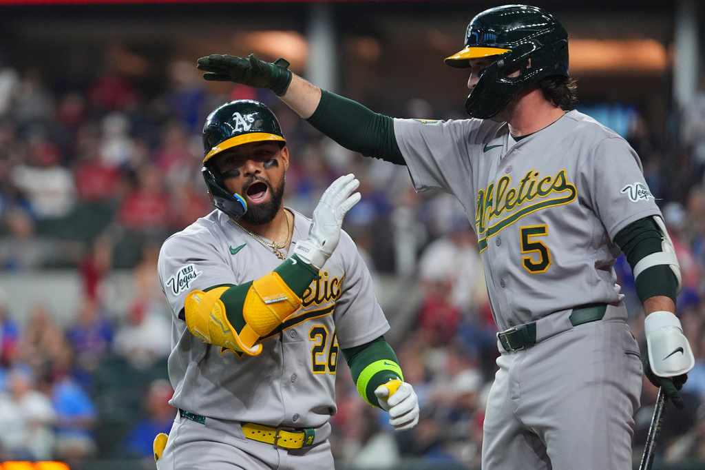 Athletics' Carlos Cortes, left, is greeted by Jacob Wilson after hitting a solo home run off Texas Rangers starting pitcher Nathan Eovaldi during the first inning of a baseball game Friday, April 24, 2026, in Arlington, Texas. (AP Photo/Julio Cortez)