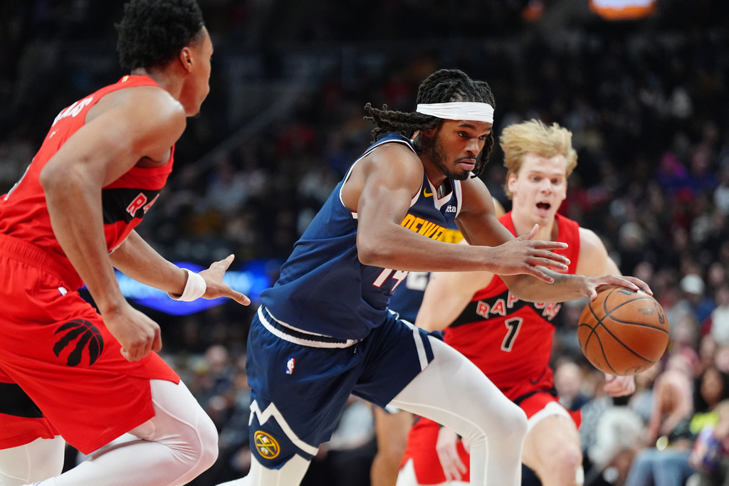 Denver Nuggets forward Daron Holmes II (14) drives up court between Toronto Raptors' Scottie Barnes, left, and Raptors guard Gradey Dick (1) during the first half of an NBA basketball game in Toronto on Wednesday, Dec. 31, 2025. (Frank Gunn/The Canadian Press via AP)