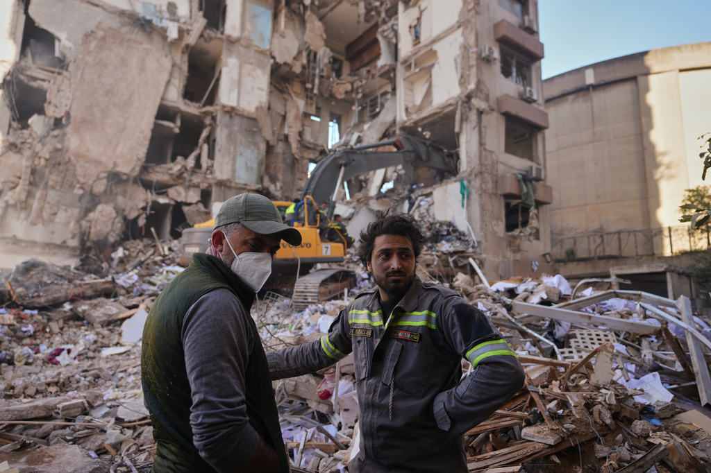 A Lebanese civil defense worker, right, stands with a resident at the site of a building destroyed in an Israeli airstrike a day earlier in central Beirut, Lebanon, Thursday, April 9, 2026. (AP Photo/Hassan Ammar)