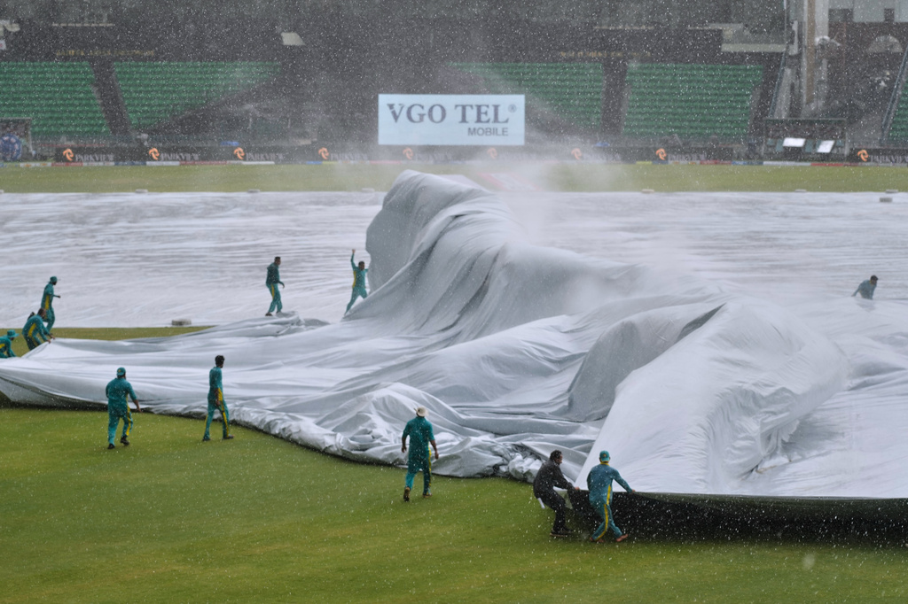 Ground staff cover pitch and surrounding area during heavy rain at the Gaddafi Stadium before start of the third one-day international cricket match between Pakistan and Australia, in Lahore, Pakistan, Thursday, June 4, 2026. (AP Photo/K.M. Chaudary)