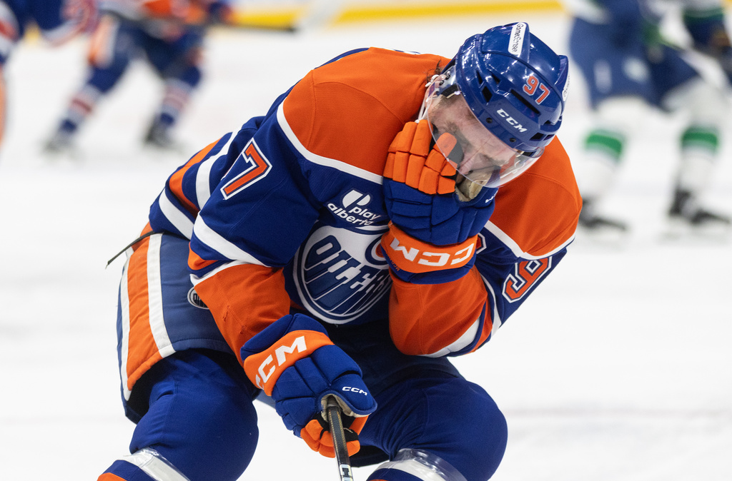 Edmonton Oilers' Connor McDavid (97) reacts to getting hit in the face with a stick against the Vancouver Canucks during the second period of an NHL game, in Edmonton, Thursday April 16, 2026. (Jason Franson/The Canadian Press via AP)