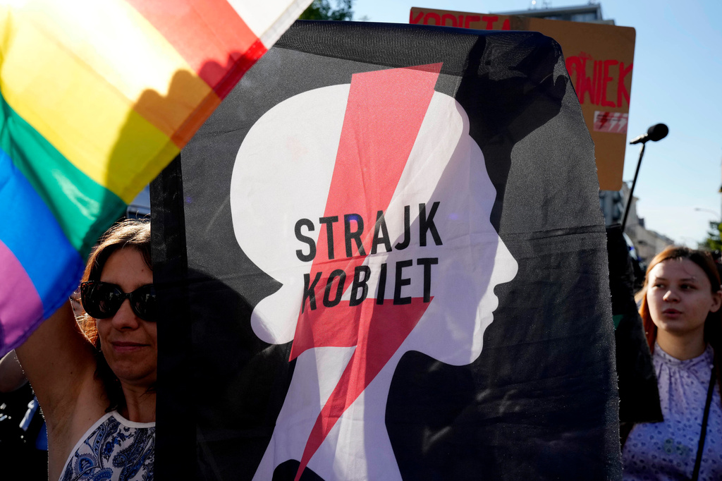 FILE - A woman with the sign of a women's rights organization and with a pro-LGBT+ rights flag take part in a protest in Warsaw, Poland, Tuesday, July 23, 2024. (AP Photo/Czarek Sokolowski, File)