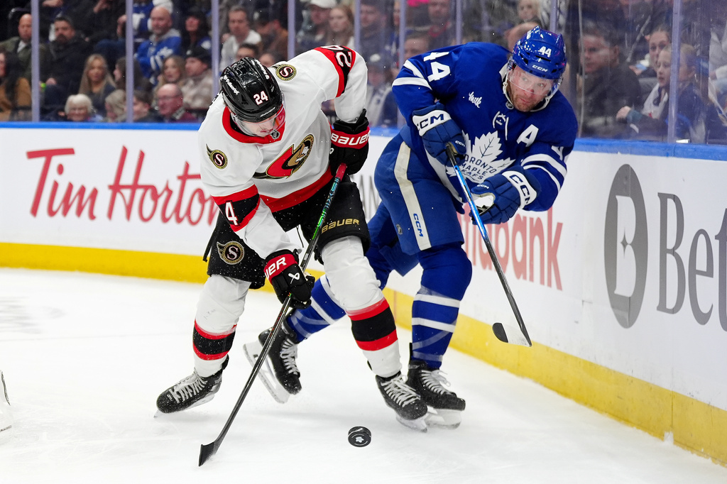 Toronto Maple Leafs defenseman Morgan Rielly, right, and Ottawa Senators center Dylan Cozens vie for control of the puck during the first period of an NHL hockey game in Toronto, Saturday, Dec. 27, 2025. (Frank Gunn/The Canadian Press via AP)