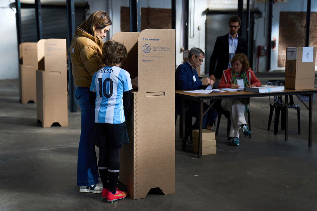 Cyntia Humbert casts her vote next to her son Silvestre Goldenhorn during legislative midterm elections in Buenos Aires, Argentina, Sunday, Oct. 26, 2025. (AP Photo/Rodrigo Abd)