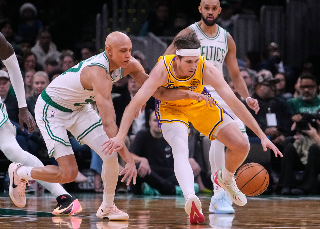 Boston Celtics guard Jordan Walsh, left, battles for a loose ball against Los Angeles Lakers guard Austin Reaves, right, during the first half of an NBA basketball game, Friday, Dec. 5, 2025, in Boston. (AP Photo/Charles Krupa)