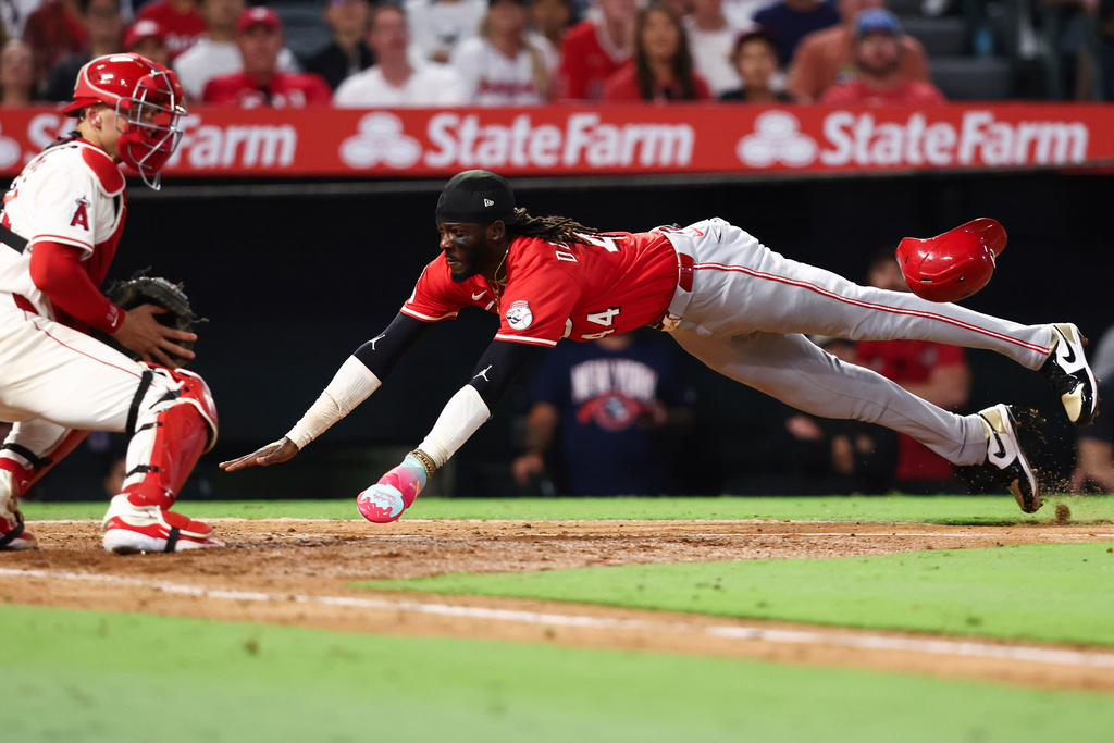 Cincinnati Reds' Elly De La Cruz, right, slides into home plate to score as Los Angeles Angels catcher Logan O'Hoppe, left, watches during the fifth inning of a baseball game, Monday, Aug. 18, 2025, in Anaheim, Calif. (AP Photo/Jessie Alcheh)