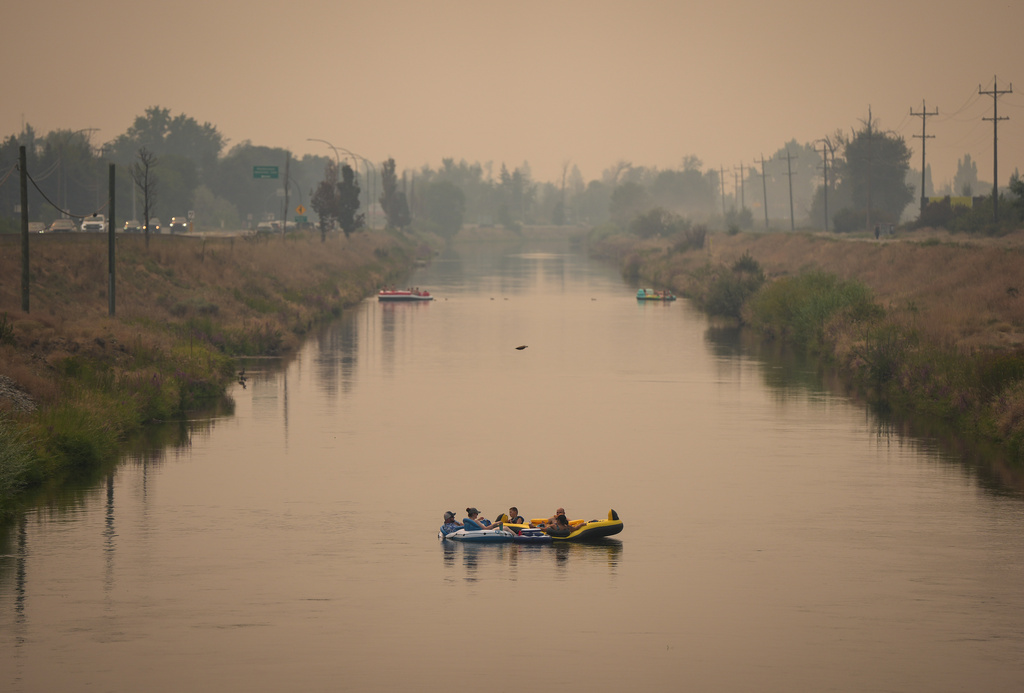 People float on the Channel Pathway that connects Okanagan Lake and Skaha Lake as smoke from wildfires burning in the region fills the air, in Penticton, British Columbia, Monday, Aug. 10, 2026. (Darryl Dyck/The Canadian Press via AP)