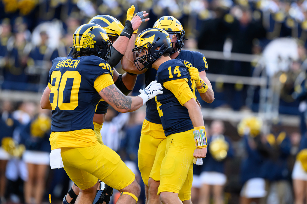 Michigan quarterback Tommy Carr (14) celebrates in the end zone with tight end Hogan Hansen (80) and wide receiver JJ Buchanan, right, after thinking he had scored a touchdown against Penn State in the third quarter an NCAA college football game, Saturday, Oct. 17, 2026, in Ann Arbor, Mich. After review it was determined that Carr's knee had touched down before he crossed over the goal line. (AP Photo/Lon Horwedel)