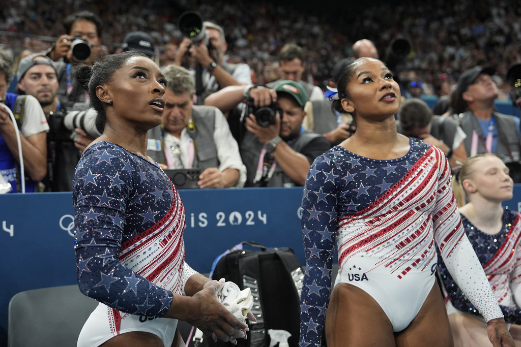 Simone Biles, and Jordan Chiles of the United States, prepare to perform on the uneven bars during the women's artistic gymnastics team finals round at Bercy Arena at the 2024 Summer Olympics, Tuesday, July 30, 2024, in Paris, France. (AP Photo/Charlie Riedel)