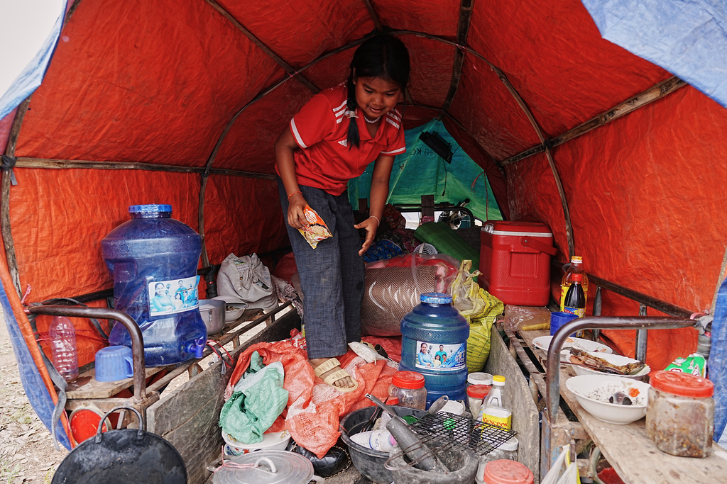 An evacuated young girl collects food in a tent as she takes refuge in Batthkoa primary school in Oddar Meanchey province, Cambodia, Wednesday, Dec. 10, 2025, after fleeing home following fighting between Thailand and Cambodia over territorial claims. (AP Photo/Heng Sinith)