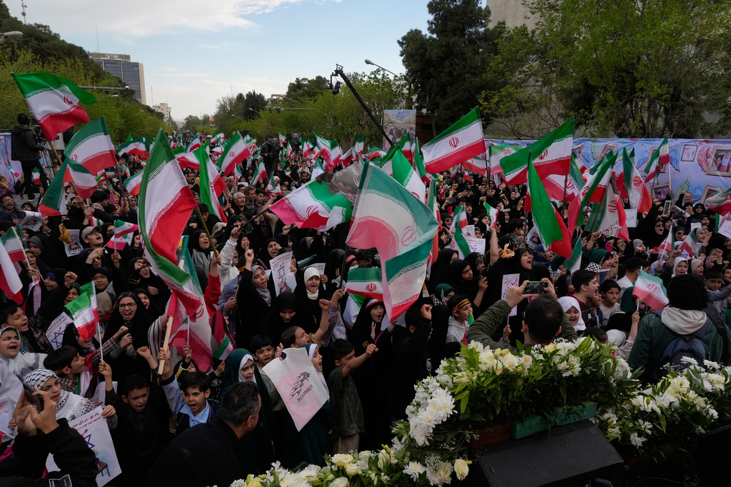People wave Iranian flags and chant slogans in a memorial for school children who were killed during a strike on a school in southern town of Minab on Feb. 28, in downtown Tehran, Iran, Tuesday, April 7, 2026. (AP Photo/Vahid Salemi)