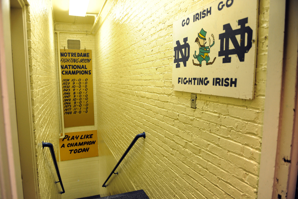 FILE - The hallway between the locker room and the field at Notre Dame Stadium features a sign "Play like a Champion Today" displayed Monday Nov. 21, 2011. Notre Dame football players on their way to the field for a game tap the sign. (AP Photo/Joe Raymond, File)