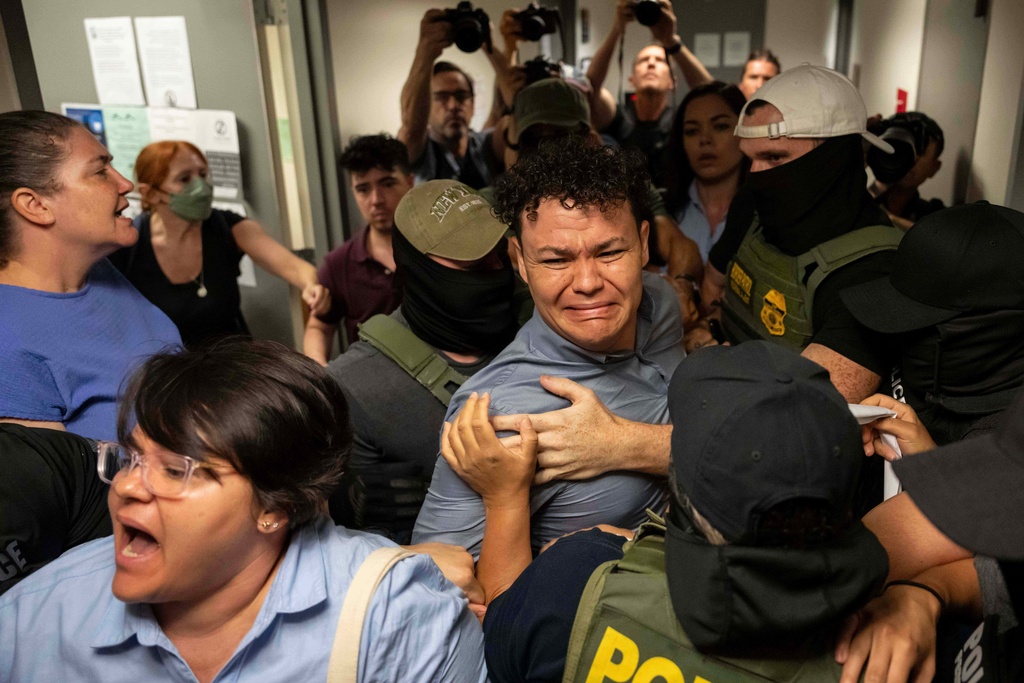 Federal agents detain Carlos Javier Lopez Benitez, center, from Paraguay as they pull away his American sister, left, outside immigration court at the Jacob K. Javits federal building, July 16, 2025, in New York. (AP Photo/Yuki Iwamura, File)