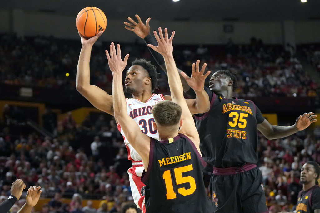 Arizona forward Tobe Awaka shoots past the defense of Arizona State's guard Noah Meeusen and center Massamba Diop during the first half of an NCAA college basketball game, Saturday, Jan. 31, 2026, in Tempe, Ariz. (AP Photo/Rick Scuteri)