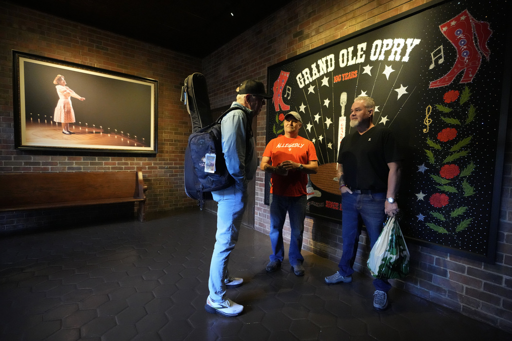 Songwriter Brian White, left, meets Army veterans Clay Jensen, center, and David Booth, right, in the entrance of the Grand Ole Opry House on Tuesday, Sept. 8, 2025, in Nashville, Tenn. (AP Photo/Mark Humphrey)