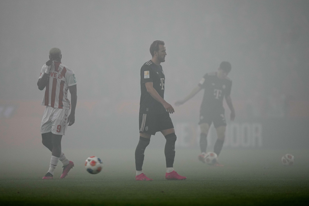 Bayern's Harry Kane, center, walks on the pitch covered in smoke from flares during the German Bundesliga soccer match between 1.FC Koeln and FC Bayern Munich in Cologne, Germany, Wednesday, Jan. 14, 2026. (AP Photo/Martin Meissner)