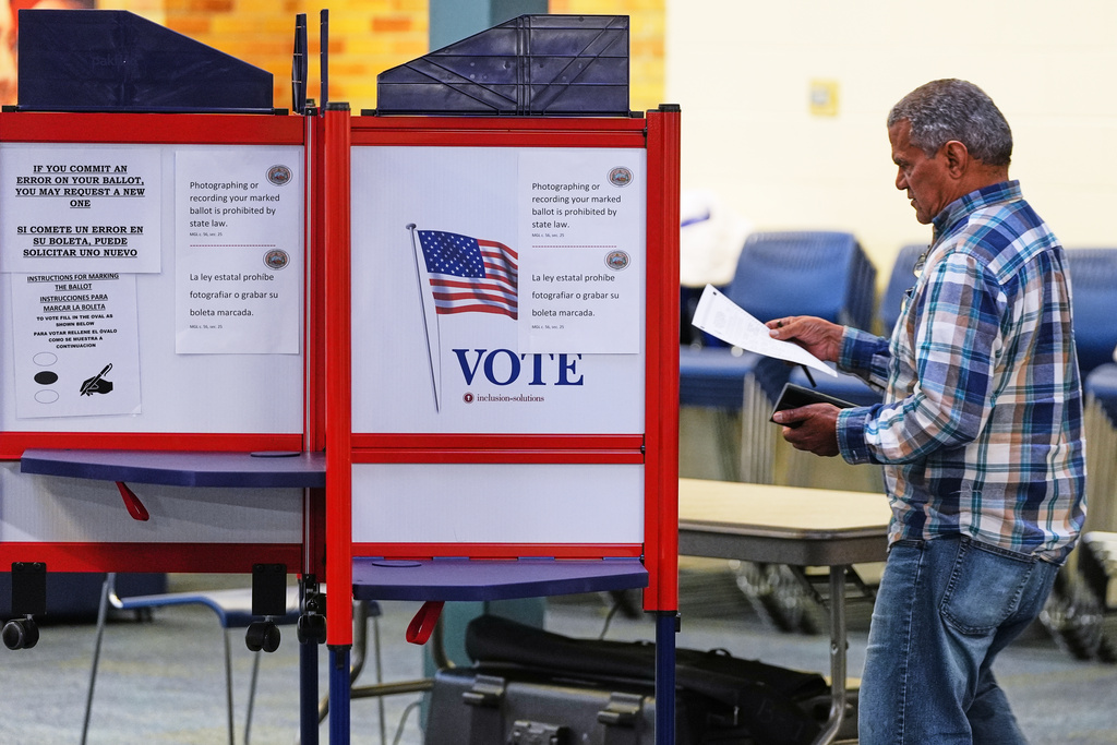 FILE - A voter carries his ballot to a booth at a polling station, Nov. 4, 2025, in Lawrence, Mass. (AP Photo/Charles Krupa, File)