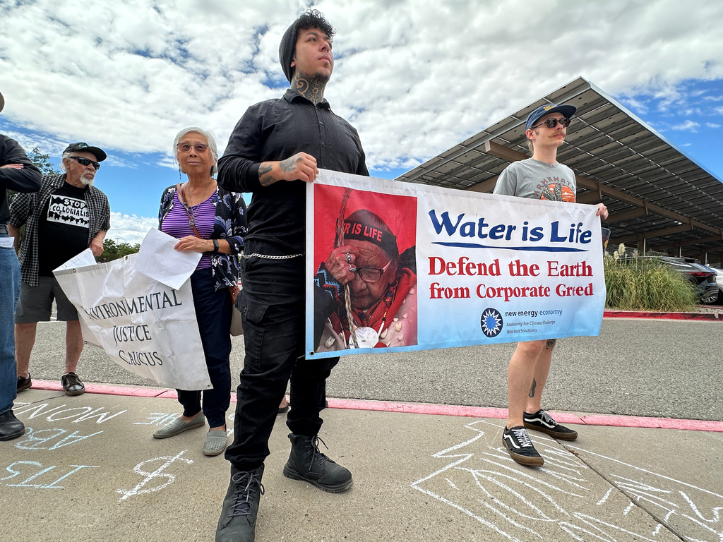 Protesters hold signs in opposition of the Project Jupiter data center during a demonstration outside a state office in Santa Fe, N.M., Friday, Aug. 21, 2026. (AP Photo/Susan Montoya Bryan)