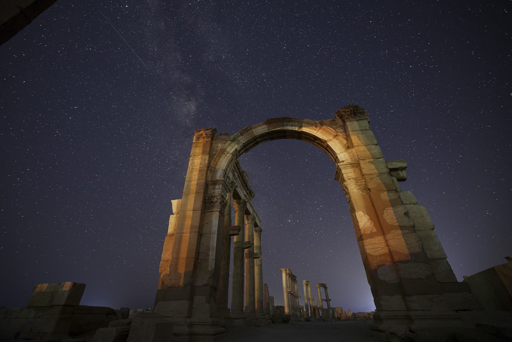 The entrance to the Roman Theater's precinct, part of the ruins of the ancient city of Palmyra, is seen under a star-studded sky in Syria, late Wednesday, Aug. 27, 2025. (AP Photo/Ghaith Alsayed)