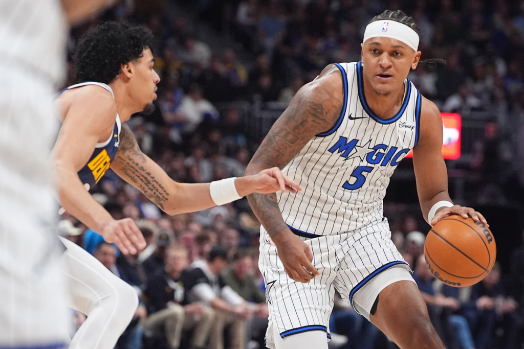 Orlando Magic forward Paolo Banchero, right, drives past Denver Nuggets guard Julian Strawther in the first half of an NBA basketball game, Thursday, Dec. 18, 2025, in Denver. (AP Photo/David Zalubowski)