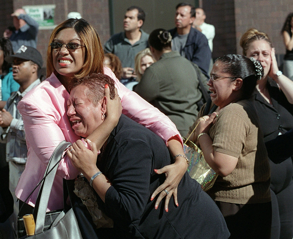 FILE - Two women embrace each other as they watch the World Trade Center burn following a terrorist attack on the twin skyscrapers in New York, Sept. 11, 2001. (AP Photo/Ernesto Mora, File)