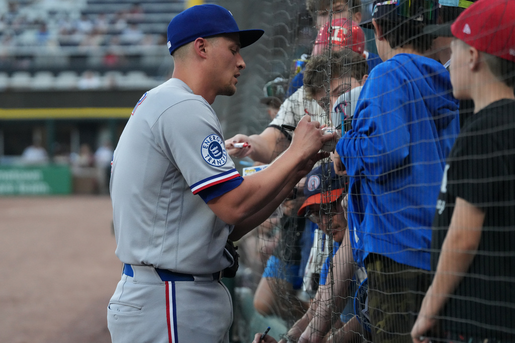 Texas Rangers shortstop Corey Seager signs autographs before a baseball game against the Chicago White Sox Tuesday, Aug. 25, 2026, in Chicago. (AP Photo/David Banks)