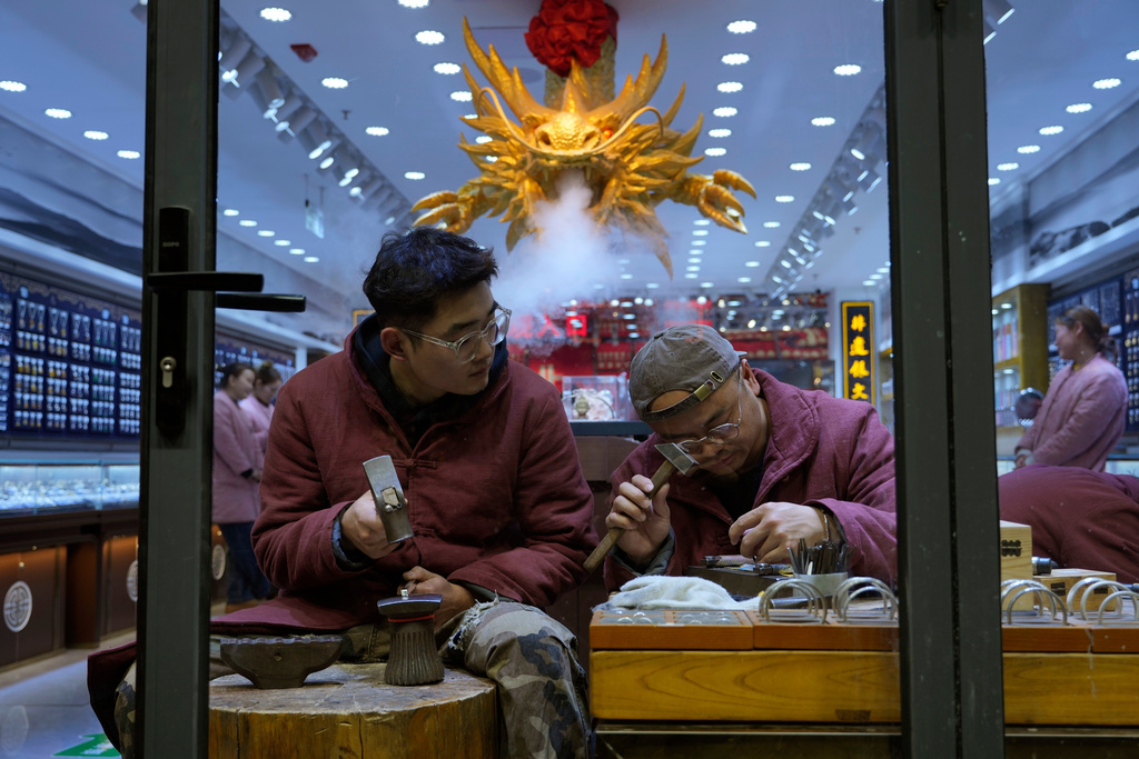 Workers hammer silver jewelry into shape at a shop in Beijing, Thursday, Dec. 18, 2025. (AP Photo/Ng Han Guan)