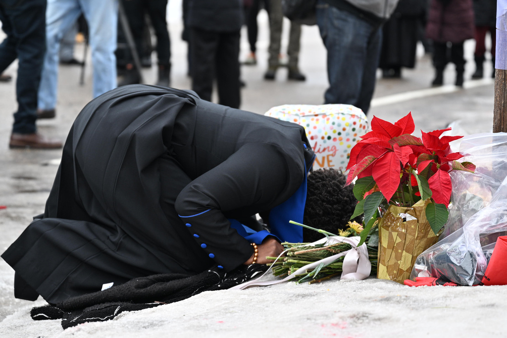 A person kneels to the ground at the makeshift memorial honoring the victim of a fatal shooting involving federal law enforcement agents, near the site of the shooting, Thursday, Jan. 8, 2026, in Minneapolis. (AP Photo/Tom Baker)