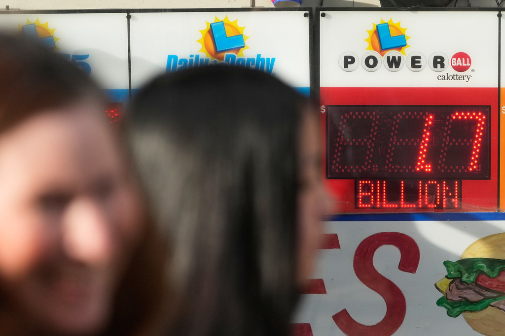 Pedestrians walk past a sign showing the Powerball jackpot of over one billion dollars at Rossi's Deli in San Francisco, Wednesday, Dec. 24, 2025. (AP Photo/Jeff Chiu)