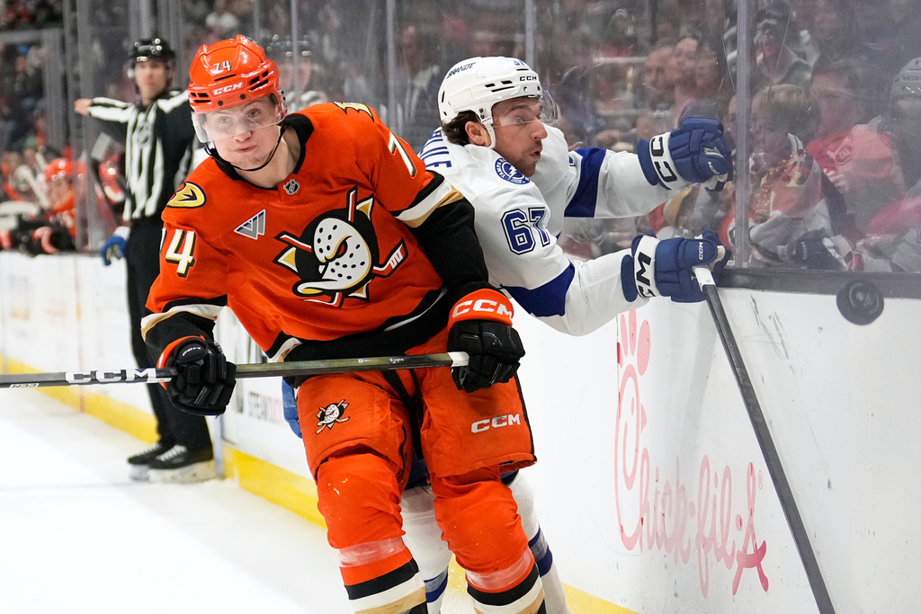 Anaheim Ducks defenseman Ian Moore, left, puts Tampa Bay Lightning defenseman Declan Carlile into the boards during the second period of an NHL hockey game Wednesday, Dec. 31, 2025, in Anaheim, Calif. (AP Photo/Mark J. Terrill)
