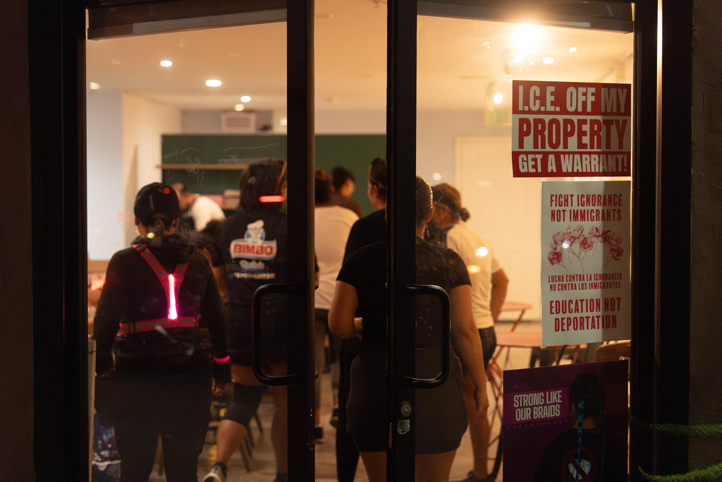 Members of the Huntington Park Run Club enter a pop-up coffee shop set up inside an art gallery in Huntington Park, Calif., Sept. 24, 2025, as signs on the door call for immigrant rights. (AP Photo/Jae C. Hong)
