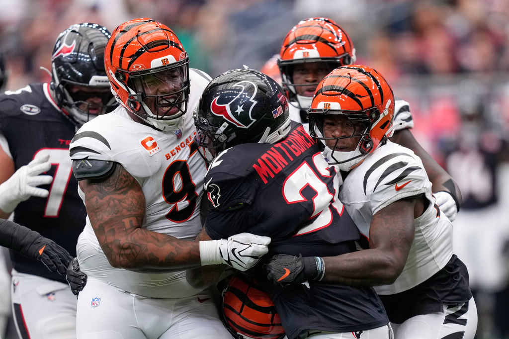 Cincinnati Bengals defensive tackle Dexter Lawrence II, left, and inside linebacker Oren Burks, right, tackle Houston Texans running back David Montgomery, center, for no gain during the first half of an NFL football game in Houston, Sunday, Sept. 20, 2026. (AP Photo/David J. Phillip)
