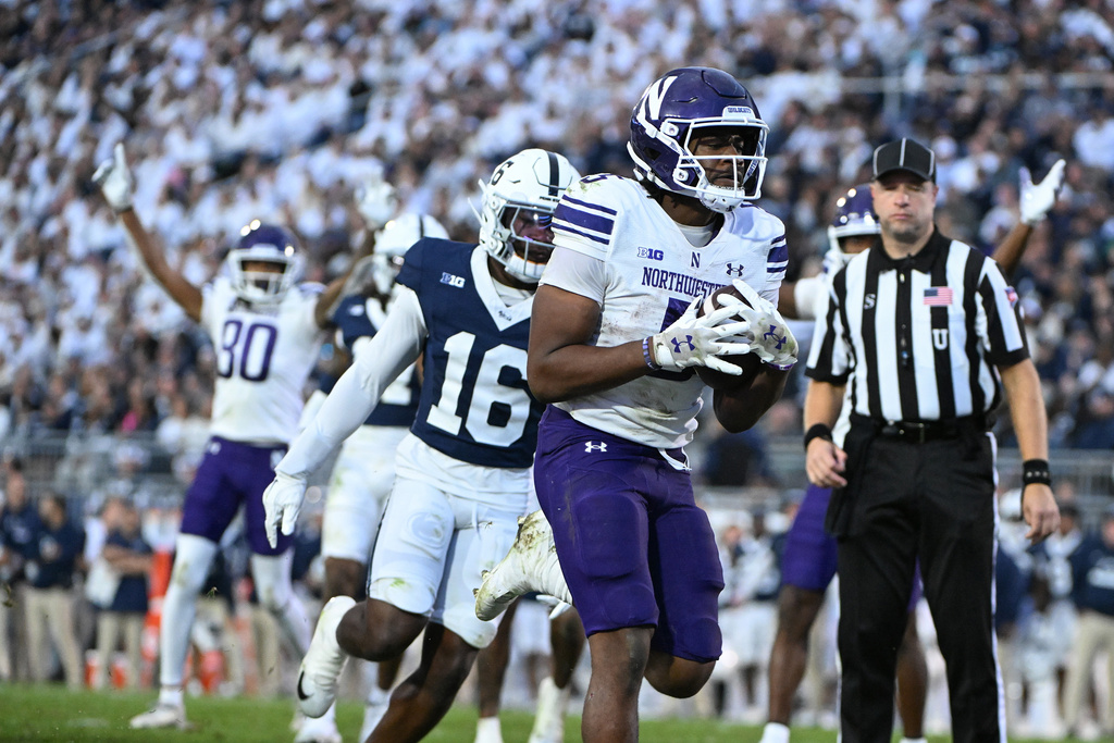 Northwestern running back Caleb Komolafe (5) scores a touchdown in front of Penn State safety King MacK (16) during the fourth quarter of an NCAA college football game, Saturday, Oct. 11, 2025, in State College, Pa. (AP Photo/Barry Reeger)