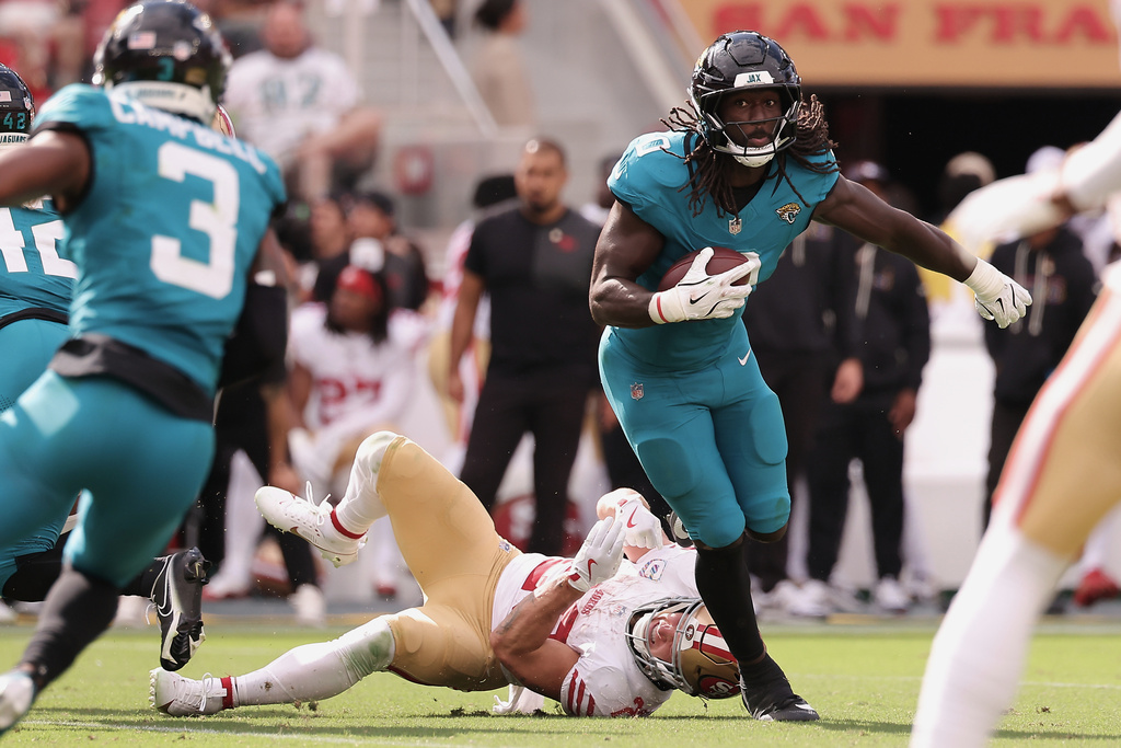 Jacksonville Jaguars linebacker Devin Lloyd, right, returns an interception against San Francisco 49ers running back Christian McCaffrey during the second half of an NFL football game in Santa Clara, Calif., Sunday, Sept. 28, 2025. (AP Photo/Kelley L. Cox)