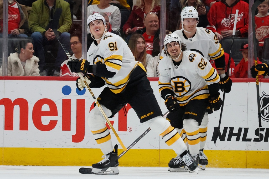 Boston Bruins defenseman Nikita Zadorov (91) smiles with teammates center Marat Khusnutdinov (92) and center Morgan Geekie (39) after scoring a goal against the Detroit Red Wings during the third period of an NHL hockey game Saturday, March 21, 2026, in Detroit. (AP Photo/Duane Burleson)