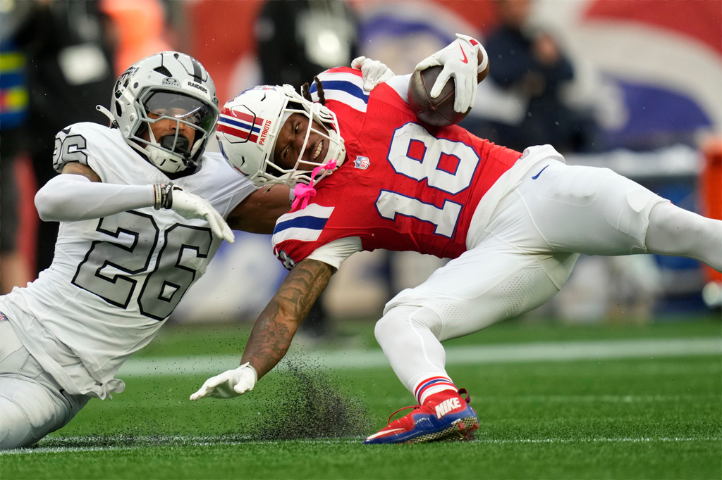 New England Patriots wide receiver Kyle Williams (18) is dragged down by Las Vegas Raiders cornerback Darien Porter (26) after catching a long pass during an NFL football game in Foxborough, Mass., Sunday, Oct. 11, 2026. (AP Photo/Charles Krupa)