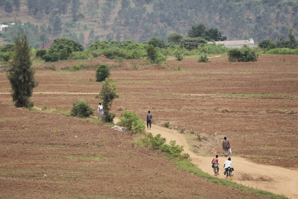 People walk and cycle along a dirt road during the men's Under 23 individual time trial event, at the road cycling World Championships in Kigali, Rwanda, Monday, Sept. 22, 2025. (AP Photo/Jerome Delay)