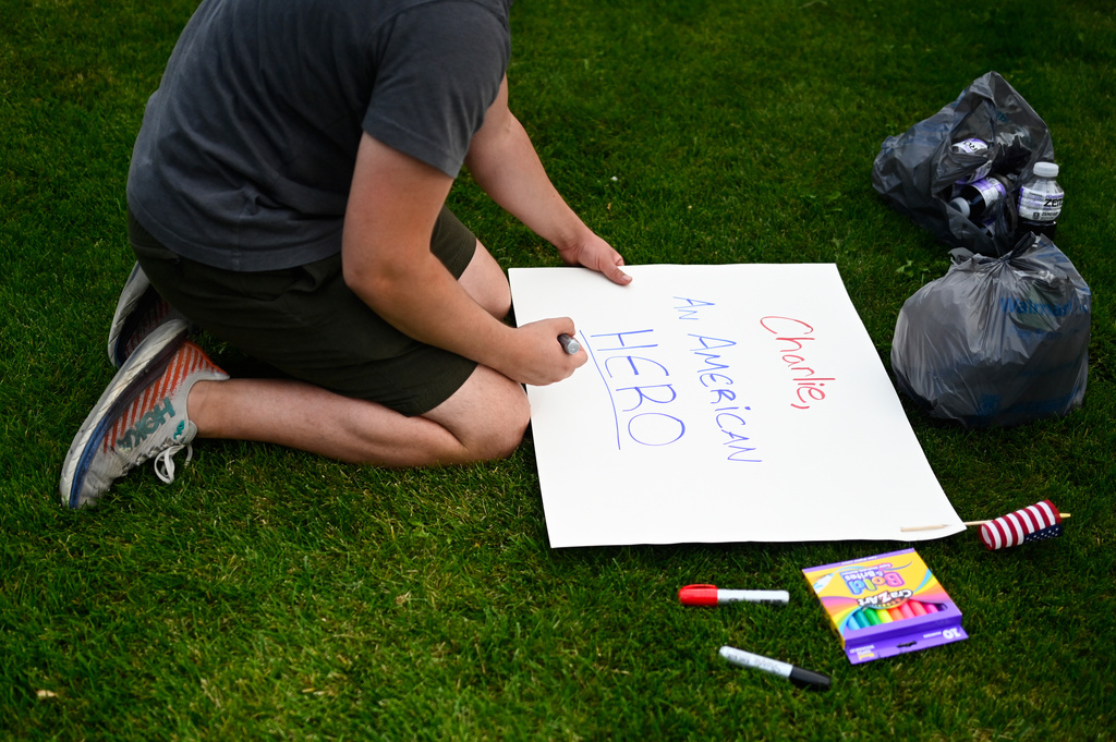An attendee makes signs at a vigil for Charlie Kirk, the CEO and co-founder of Turning Point USA, who was shot and killed at Utah Valley University earlier in the day, at Timpanogos Regional Hospital, Wednesday, Sept. 10, 2025, in Orem, Utah. (AP Photo/Alex Goodlett)